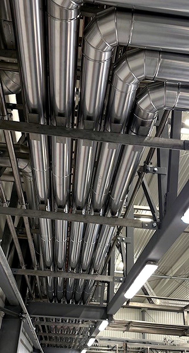 Full row of metal-clad overhead pipe runs with uniform cladding in an industrial facility